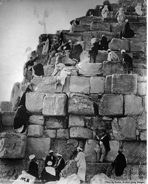 Turistas escalando uma pirâmide no Egito, nos anos 1800