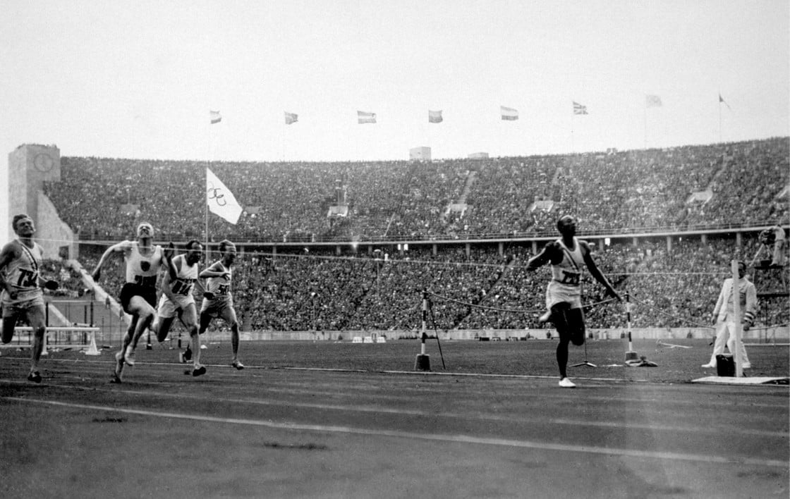 Jesse Owens cruzando a linha de chegada em Berlim para vencer os 100 metros rasos em 3 de agosto de 1936