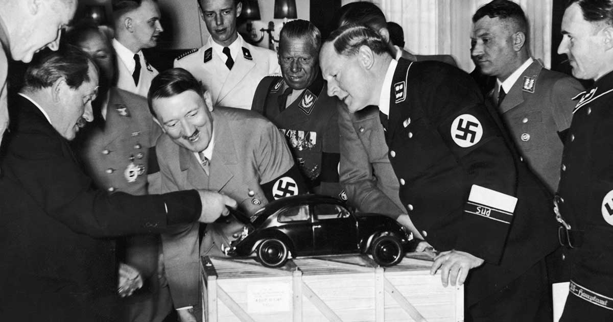 Ferdinand Porsche (esquerda) diverte o ditador alemão Hitler, mostrando-lhe um modelo de Fusca