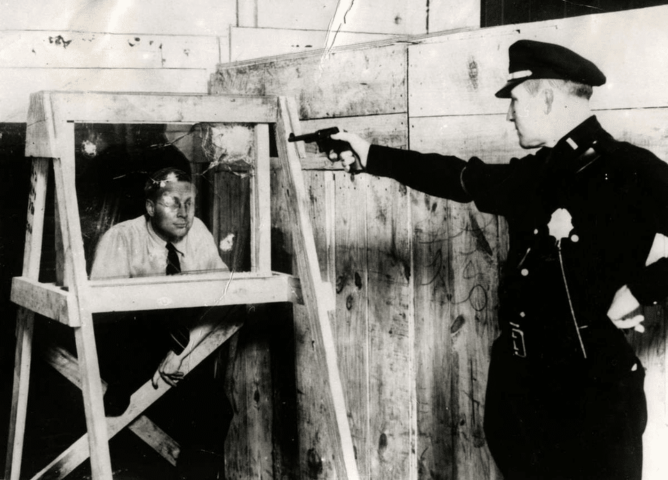 Policial novaiorquino dispara seu 38 contra um homem para comprovar que o vidro à prova de balas realmente funciona, em 1931