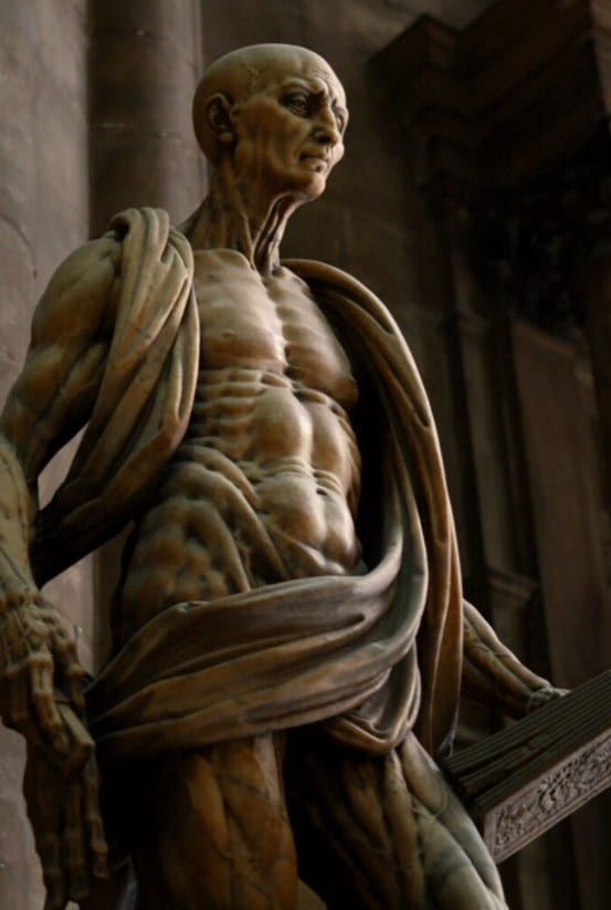 Esta estátua retrata São Bartolomeu, um dos primeiros mártires cristãos que teria sido esfolado vivo. Se você olhar com atenção, verá que não é um manto que ele está segurando. Na verdade, é sua pele dissecada pendurada ao redor dele. Estátua de Marco d'Agrate