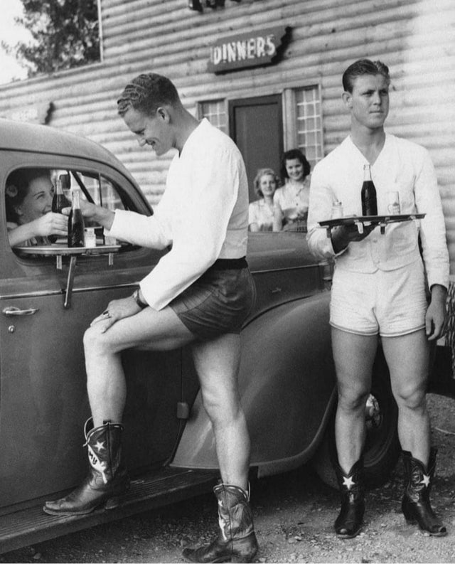 Na década de 1940, homens vestidos de botas e com shorts serviam à mulhers em um drive em Dallas, Texas.