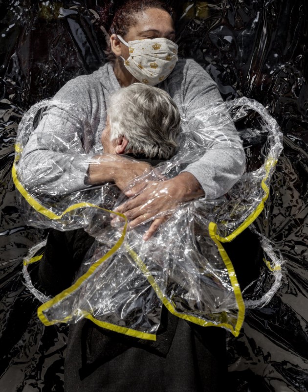 Fotografia de Mads Nissen, vencedor do principal prêmio de fotojornalismo do mundo. Ela mostra uma idosa sendo abraçada por uma enfermeira protegida por plástico durante pico da pandemia de covid-19 aqui no Brasil.