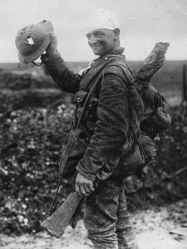 Um sortudo soldado britânico mostrando seu capacete danificado, em 1917.