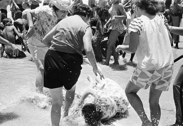 Uma mulher que apoiava manifestação anti-racista sendo atacada por três supremacistas brancas em praia segregada na Flórida, em 1964.