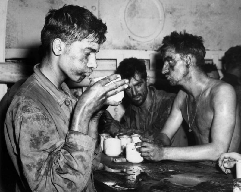 Fuzileiros navais norte-americanos fazendo uma pausa para o café após uma batalha brutal na Segunda Guerra Mundial, na década de 1940