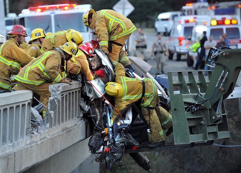 Família sendo resgatada de um carro pendurado em um viaduto na 101 Freeway, na Califórnia. Um caminhão atingiu o BMW, que tombou para o lado.