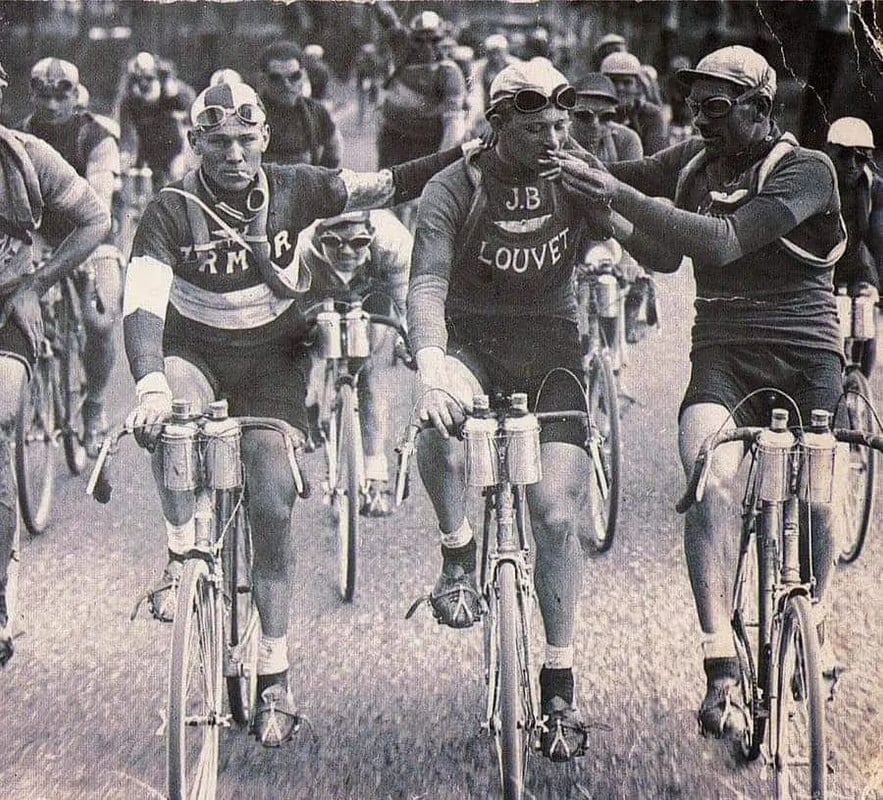 Competidores compartilhando um cigarro durante o Tour de France, 1920.