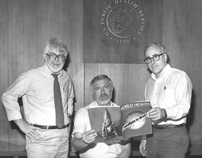 Três ex-diretores do Programa Global de Erradicação da Varíola lendo a notícia de que a doença foi erradicada globalmente, em 1980.
