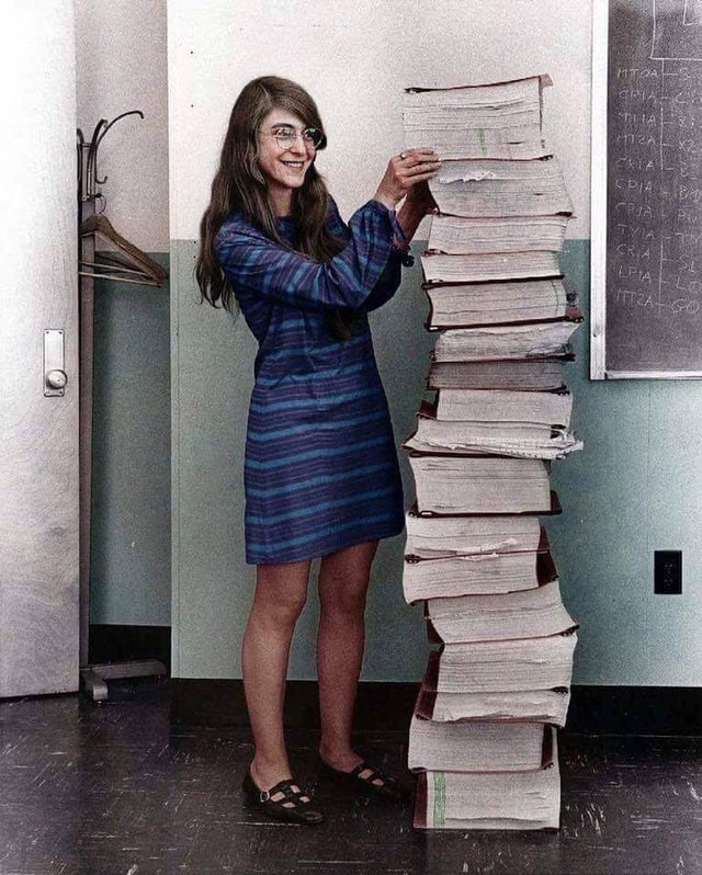 Margareth Hamilton, principal desenvolvedora da NASA para o projeto Apollo. Na foto, ela aparece ao lado de todo o código que ela escreveu à mão que levou o homem à lua, em 1969.