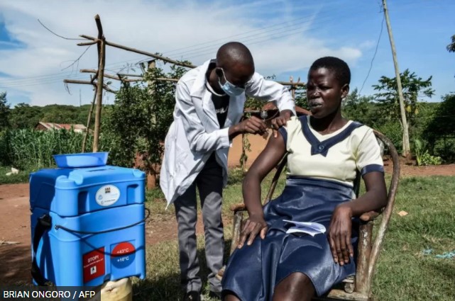 Um profissional de saúde que realiza visitas porta a porta vacina uma mulher com o imunizante contra a covid-19 em Siaya, Quênia, em maio.