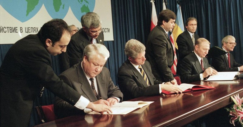 Rússia e Estados Unidos assinando um tratado onde a Ucrânia desistia de suas armas nucleares em troca de garantias de segurança, em 1994.