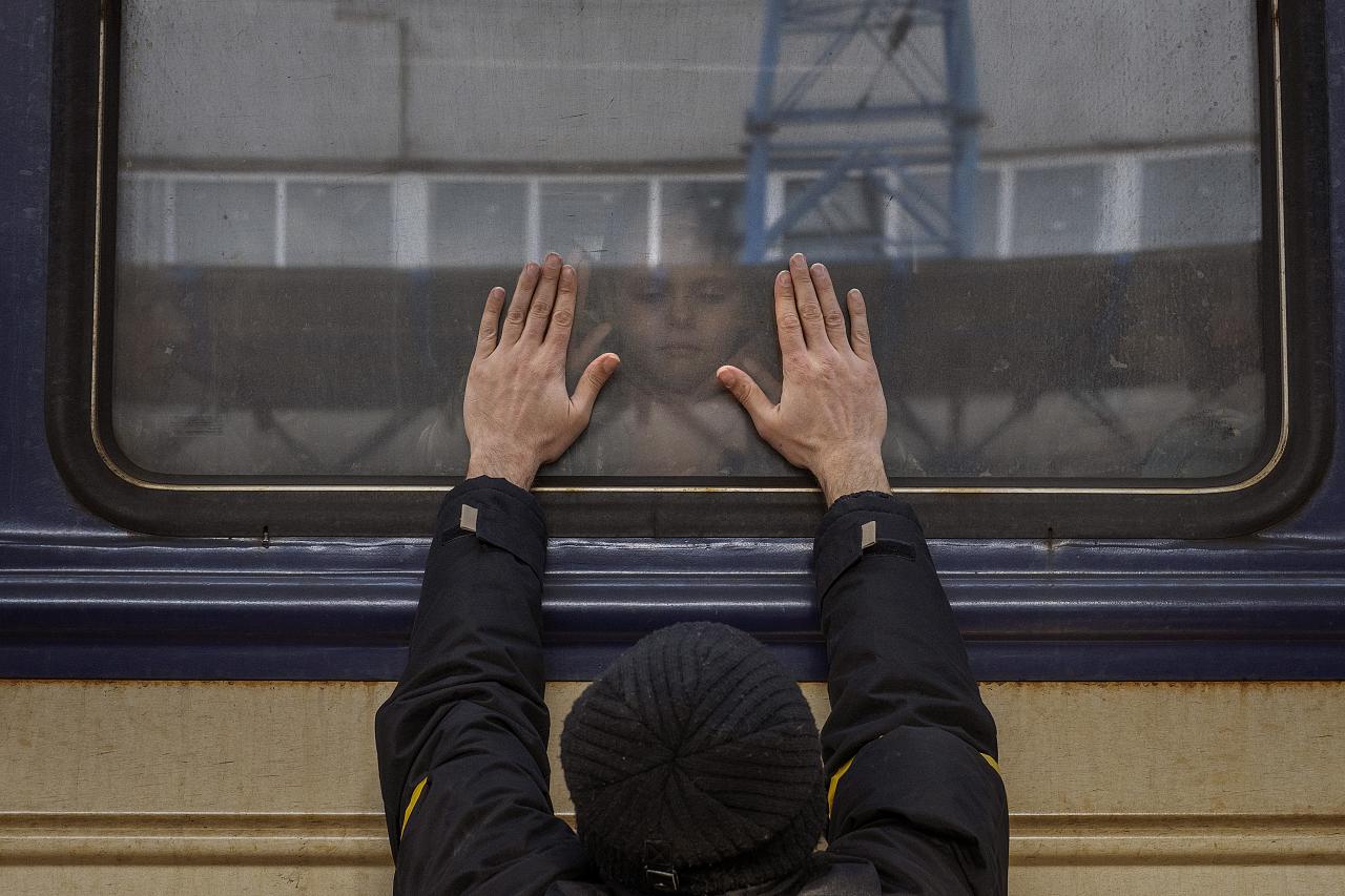 Aleksander, 41, pressiona as palmas das mãos contra a janela enquanto se despere da filha Anna, 5, em um trem para Lviv, na estação de Kiev, na Ucrânia, 4 de março de 2022.