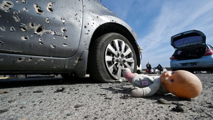 Fotografia tirada em 12 de março de 2022 mostrando uma boneca abandonada ao lado de um carro crivado de balas em Irpin, ao norte de Kiev.