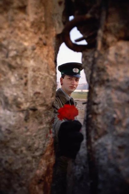 Soldado da Alemanha Oriental passando uma flor pelo Muro de Berlim antes de ser derrubado, 1989.