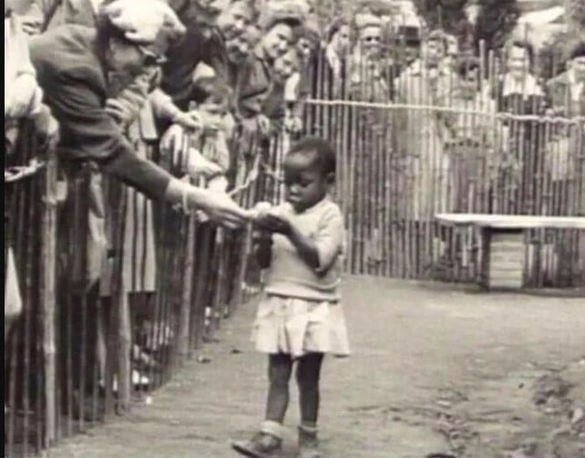Mulher alimentando uma garota africana tratada como um animal no último zoológico humano em Bruxelas, 1958.