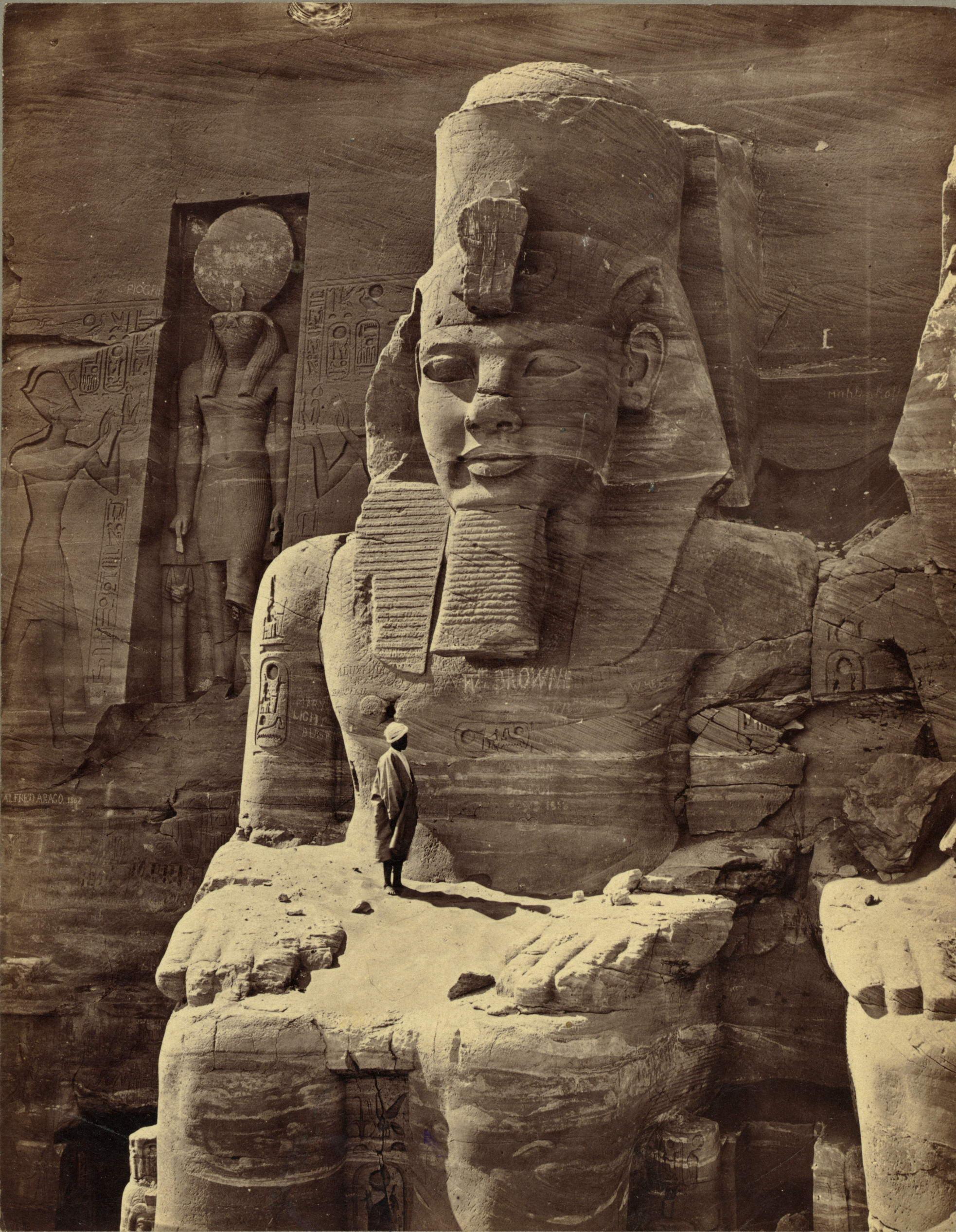 Homem de pé no colo da figura colossal de Ramsés, 1856.