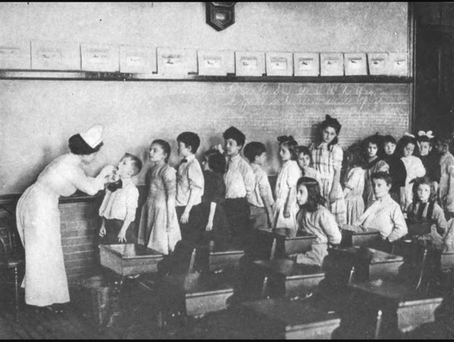 Uma enfermeira inspecionando crianças em idade escolar para amigdalite, durante o surto em 1906, em Nova Iorque.
