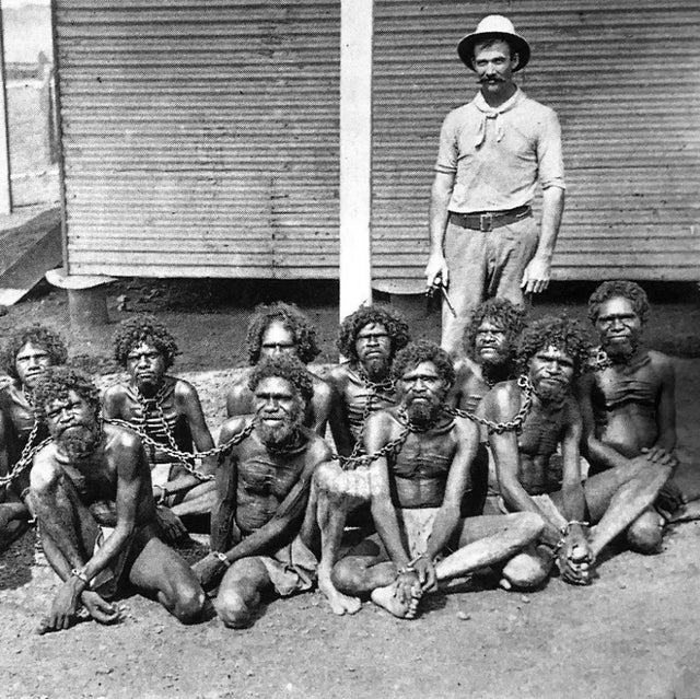 Foto de um homem britânico usando uma corente no pescoço de aborígenes, nativos da Austrália, 1900.