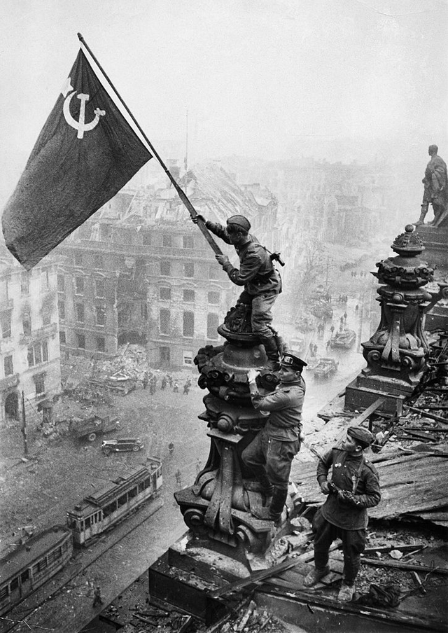 Soldados soviéticos levantam a bandeira soviética sobre o Reichstag, Berlim, Alemanha, 1945.