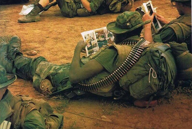 Soldados de tropa norte-americana de patrulha de reconhecimento de longo alcance no Vietnã lendo histórias em quadrinhos durante descanso - Década de 1960.