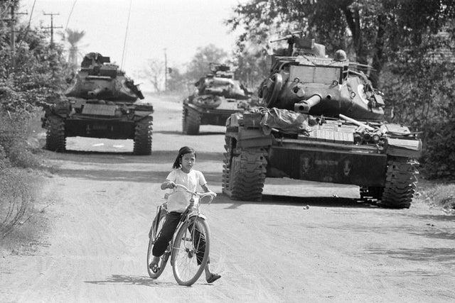 Tanques americanos atravessam estradas de terra no Vietnã do Sul, passando por uma garotinha de bicicleta, 1972.