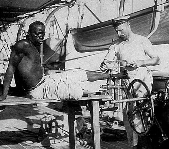 Marinheiro britânico removendo as correntes das pernas de um homem escravizado que as usava por três anos.